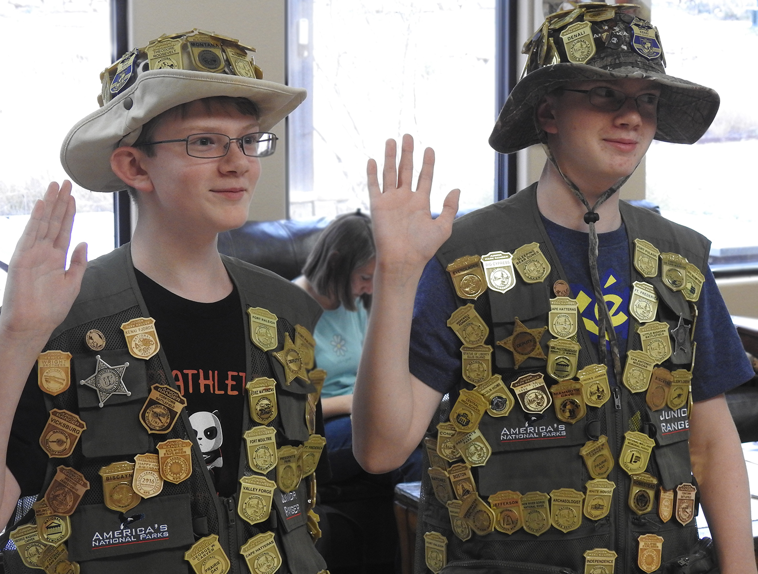 Swearing in two Jr. Rangers Swearing in two Jr. Rangers who are wearing their Jr. Ranger hats and vests covered with badges.