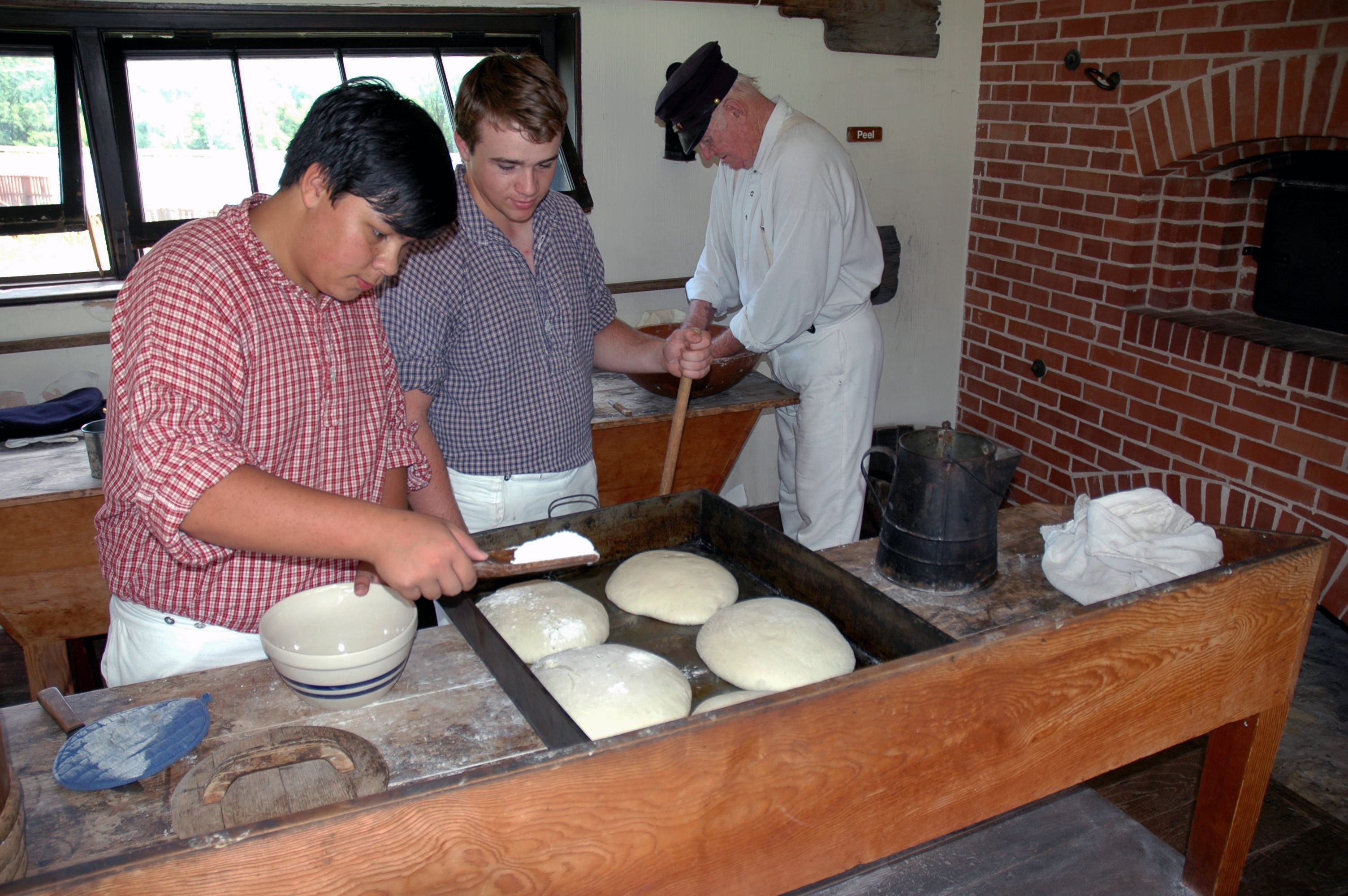 YCC Baking Bread Two YCC youth and a Park Ranger are in historic clothing baking bread.