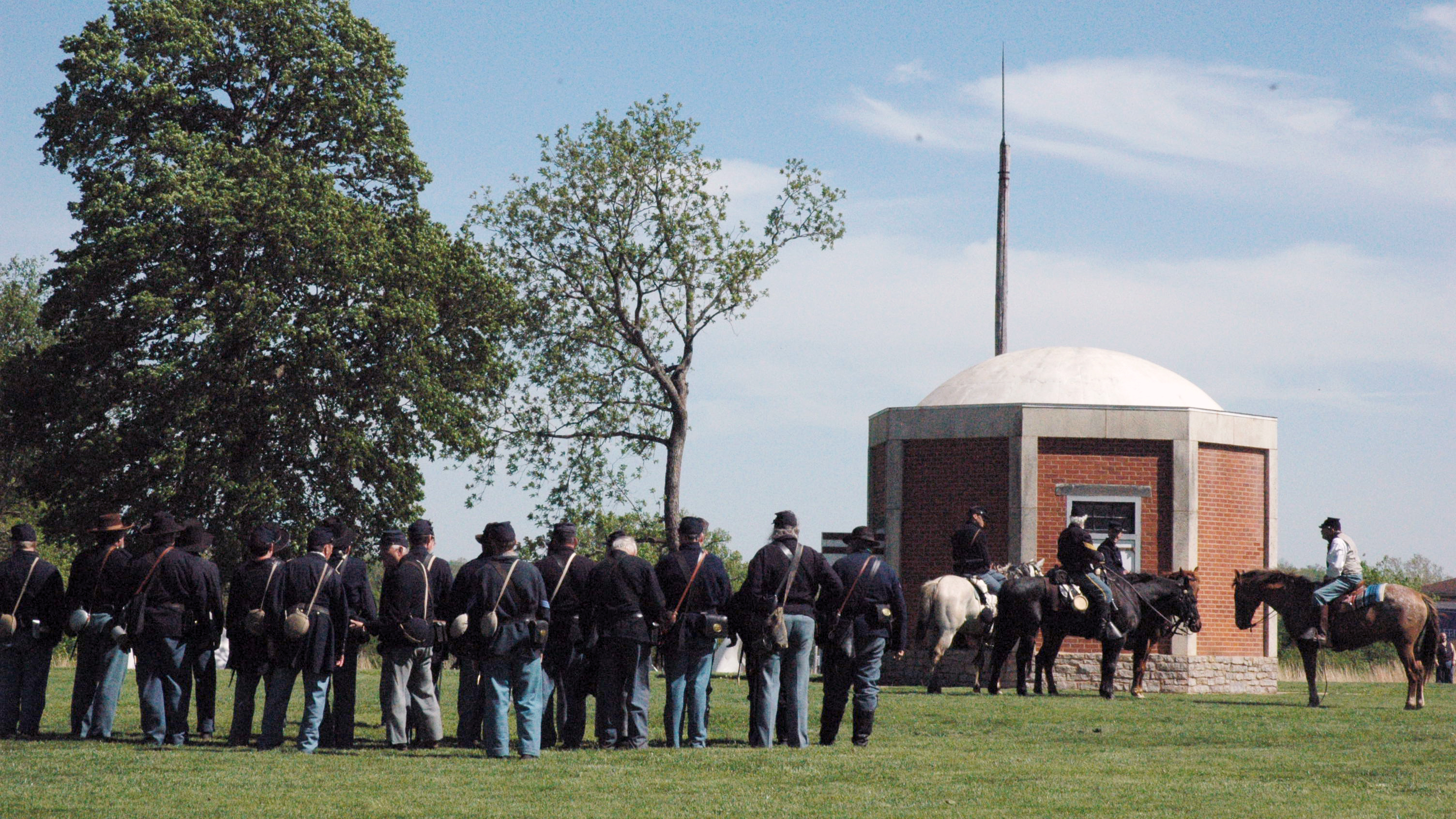 Civil War Solders dressed in blue both standing and on horseback next to the fort's powder magazine on the parade ground.