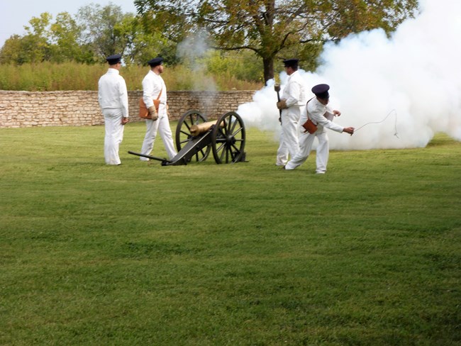 Mountian Howitzer Firing soldiers in white clothing firing cannon