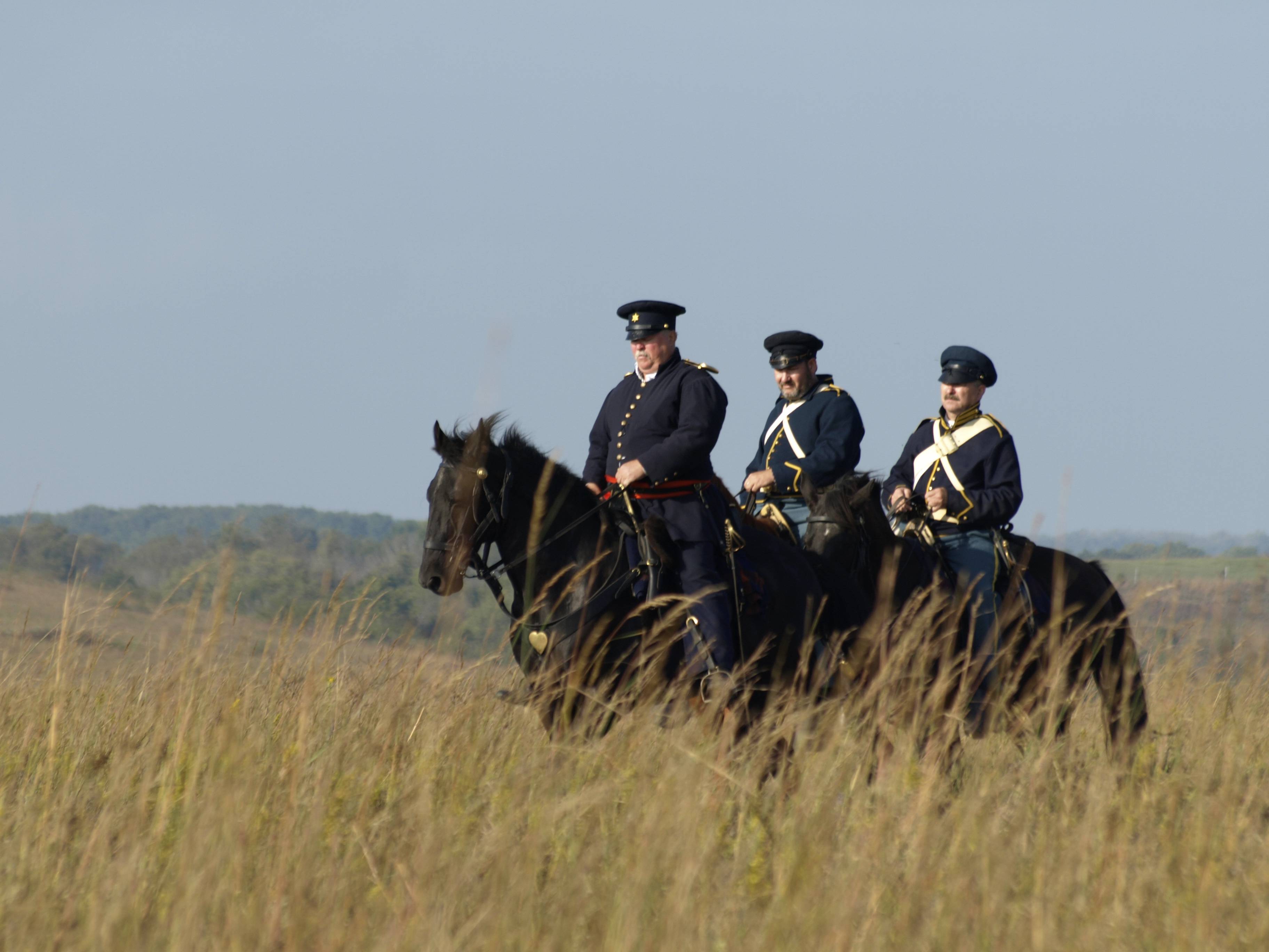 Men on horseback riding through prairie Men on horseback riding through prairie