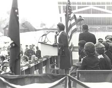 black and white photo showing Ladybird Johnson at podium during dedication of park.  American flag is behind her.