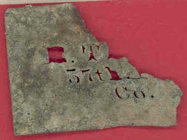thin, corroded piece of metal with small cut-out letters and numbers.  R.T. 57th Co.