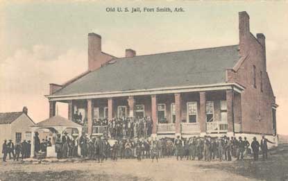 sepia postcard of people standing on grounds of old jail building
