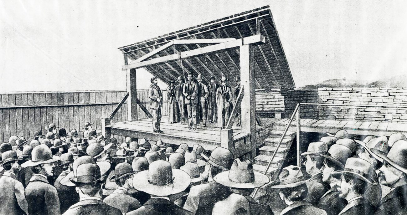 Execution of Cherokee Bill A drawing of Cherokee Bill with a noose around his neck and five other men standing on the gallows at Fort Smith surrounded by a crowd.