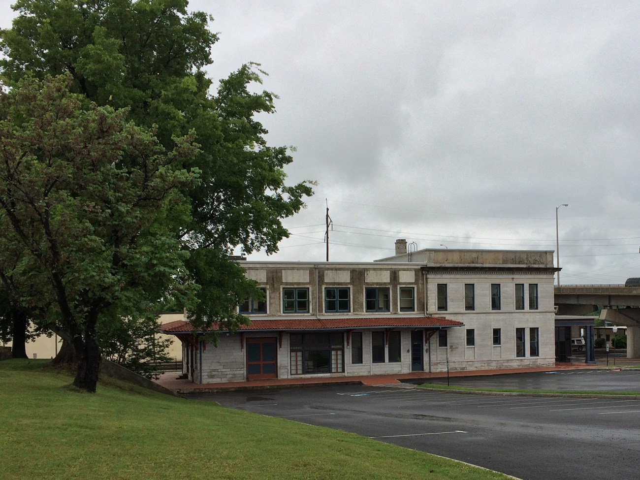 Two story white limestone structure. An awning with a terra cotta tile roof is around the left half of and side of the building.