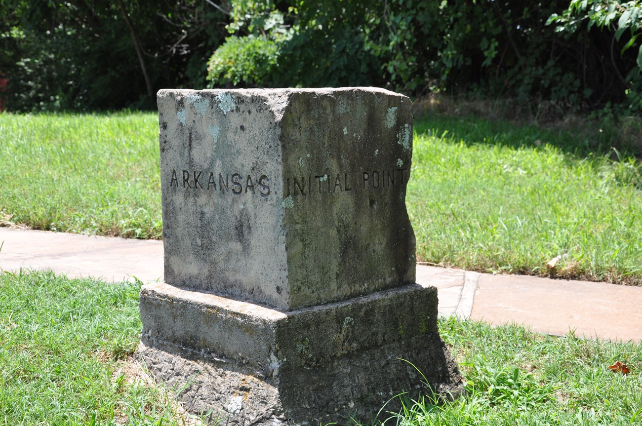 Gray stone cube surrounded by green grass on a sunny day