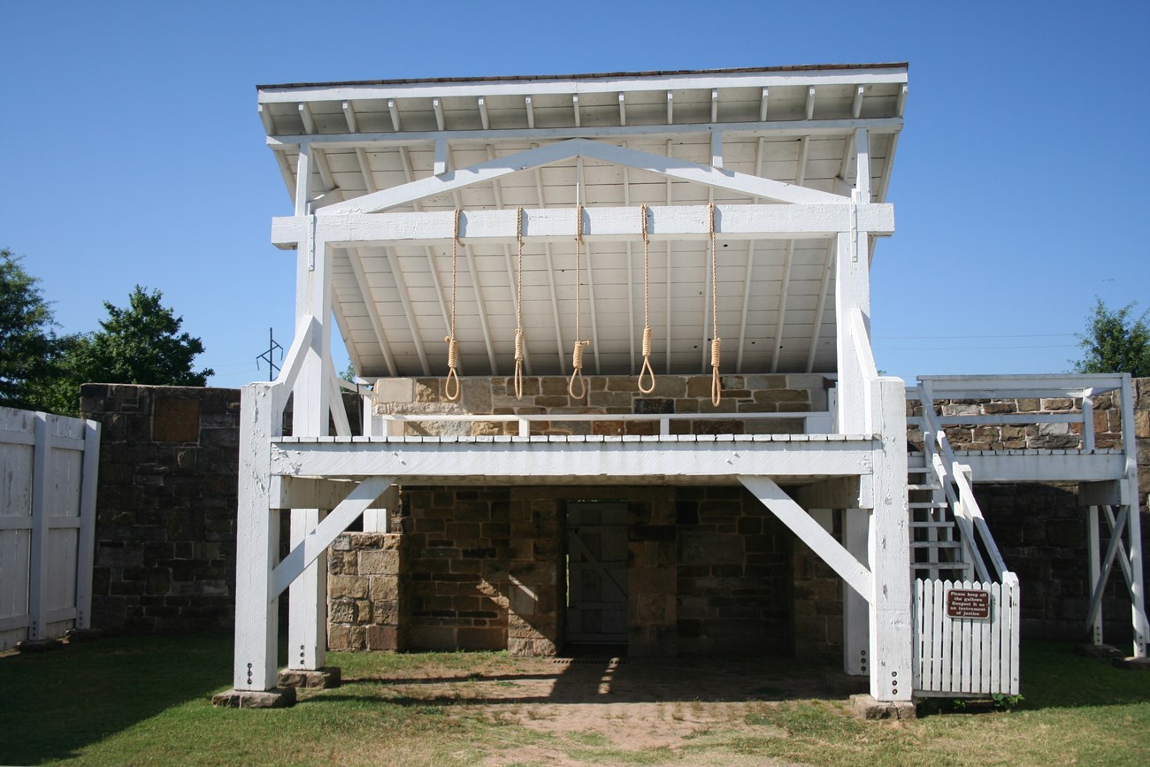 White platform with an angled roof and four nooses hanging from a crossbeam