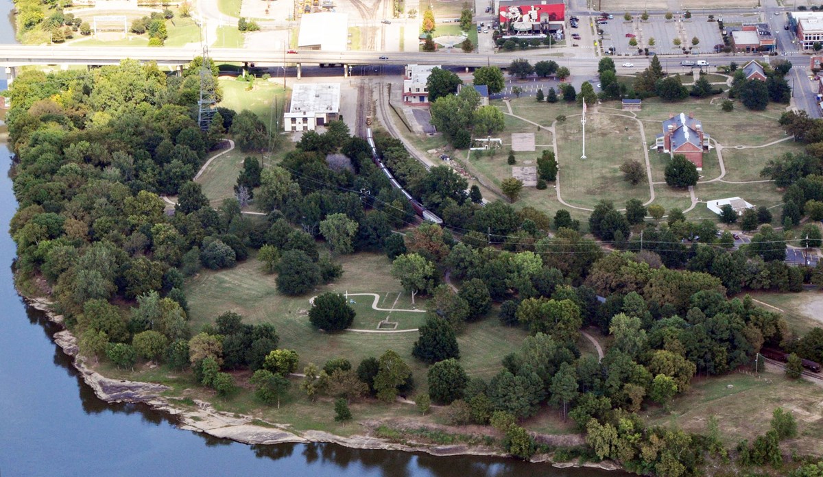 Aerial view of park grounds parts of several building and sidewalks are visible between trees