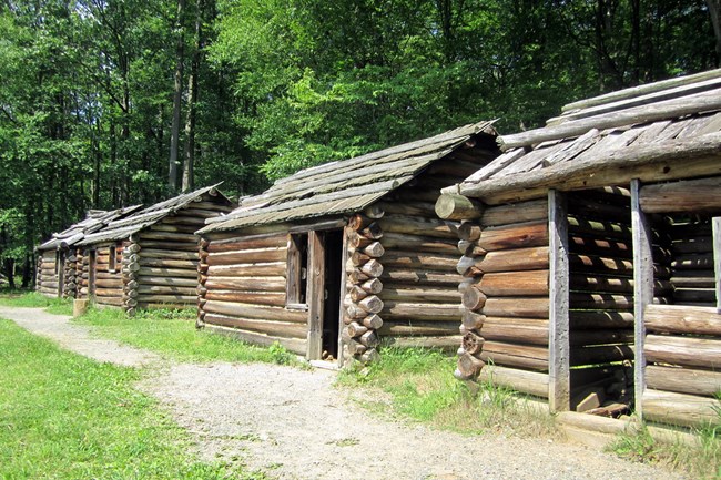 Three smallish log cabin style huts. Each can fit about four men inside. There are gaps in the walls.