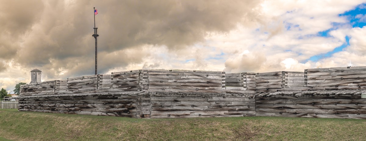 Clouds gather over the wooden walls of the fort.