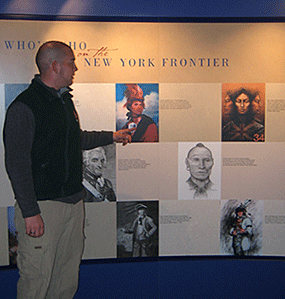 a man points to faces on a wall.