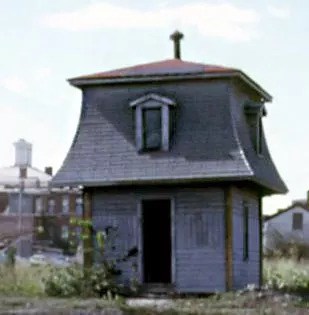 A two-story, tiny looking house with windows and blue paint.