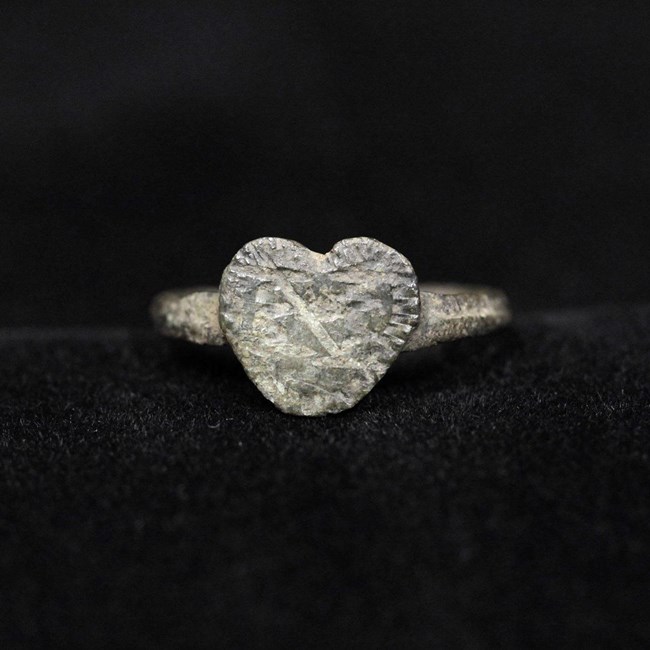 A small metal, heart-shaped item  with scratches on it.