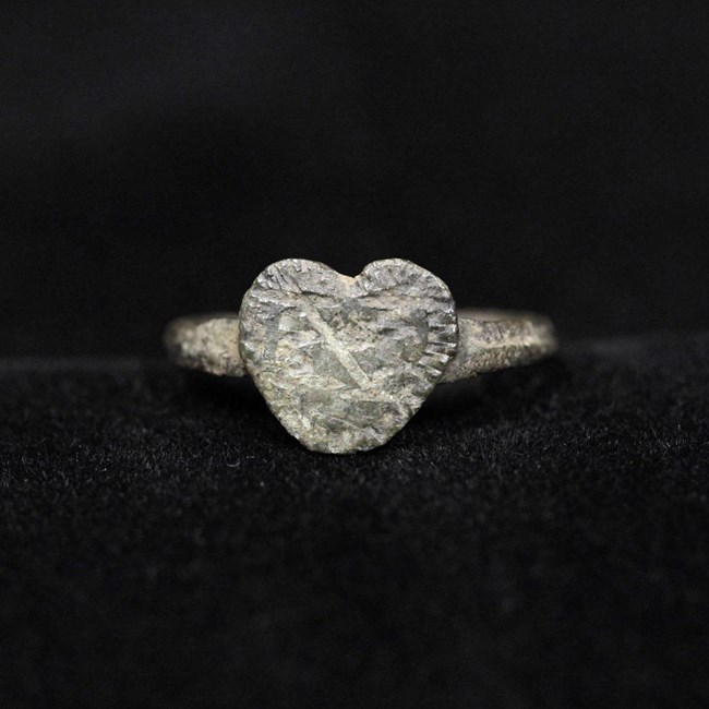 A small metal, heart-shaped item  with scratches on it.