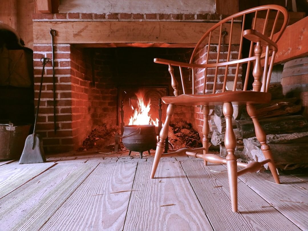 Looking from the level of a wooden floor to chair to the right of you and a brick fireplace in front.