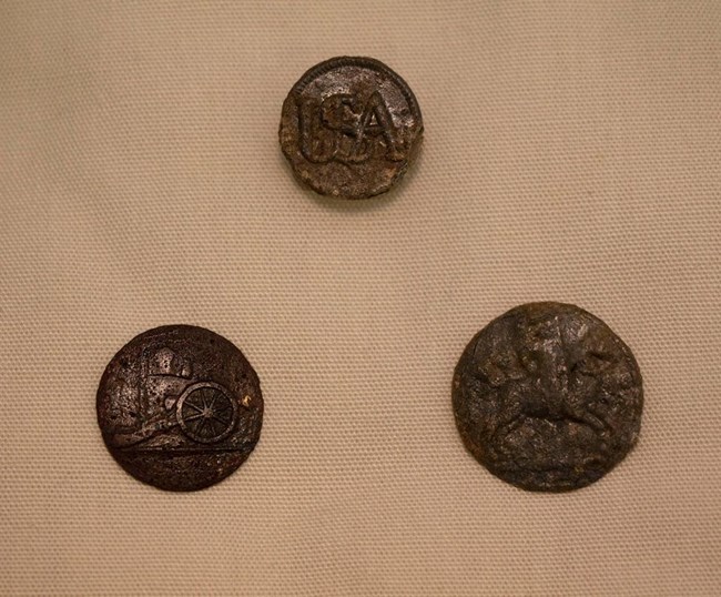 Three metal buttons. One with USA, one with a cannon, one with a horse and rider, stamped on them.
