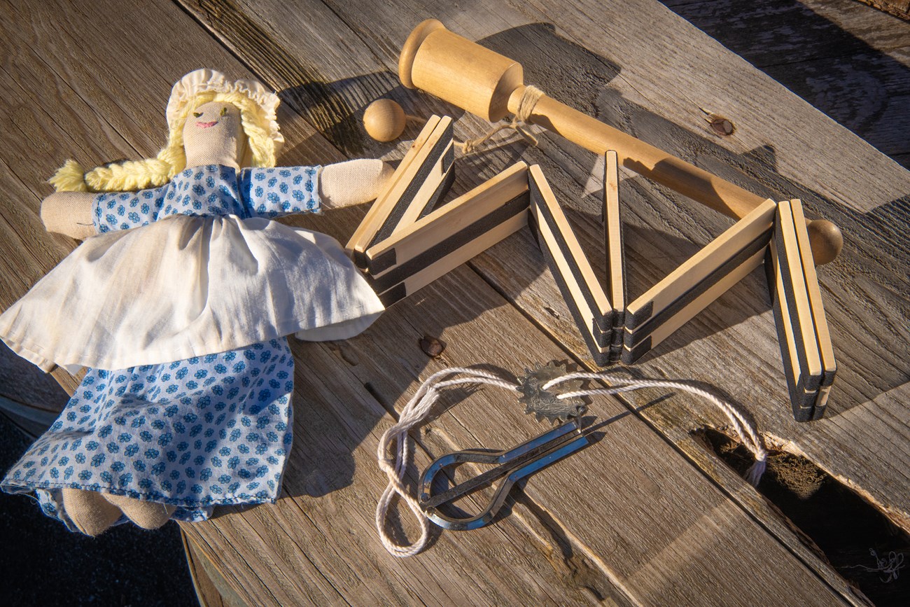 Wooden toys strewn about. There are jacob's ladders, and a cup and ball toy. There is also a cloth doll.