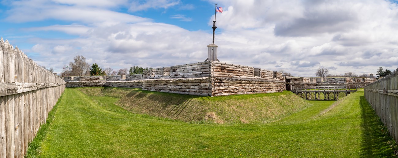 Large wooden pickets surround you as you look directly at the fort wall.