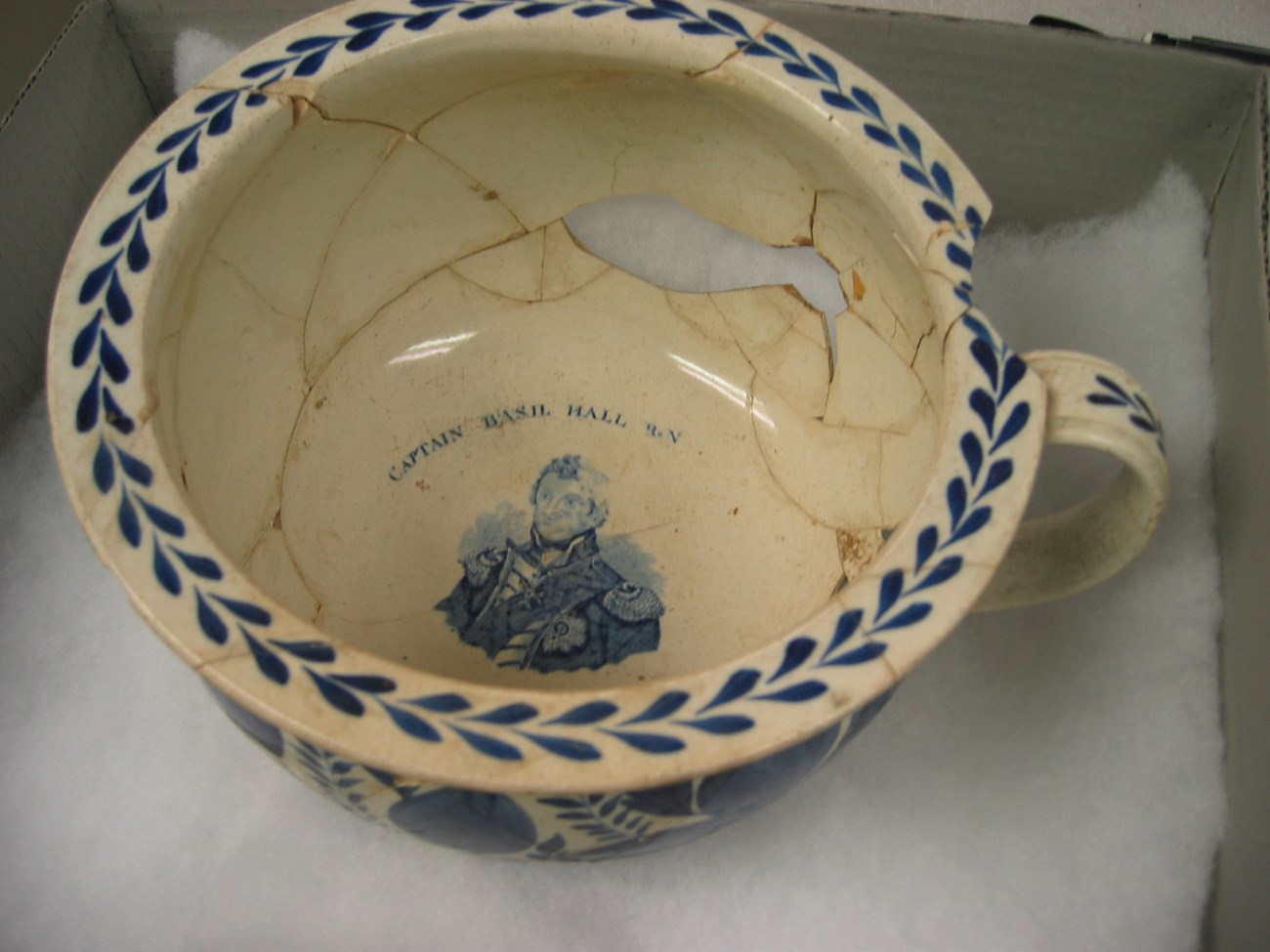 A large bowl with a mug-like handle. It has a decorative lip and a portrait of a man on the inside.