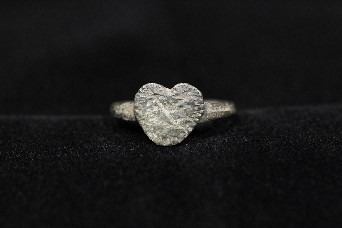A small metal, heart-shaped item with scratches on it.
