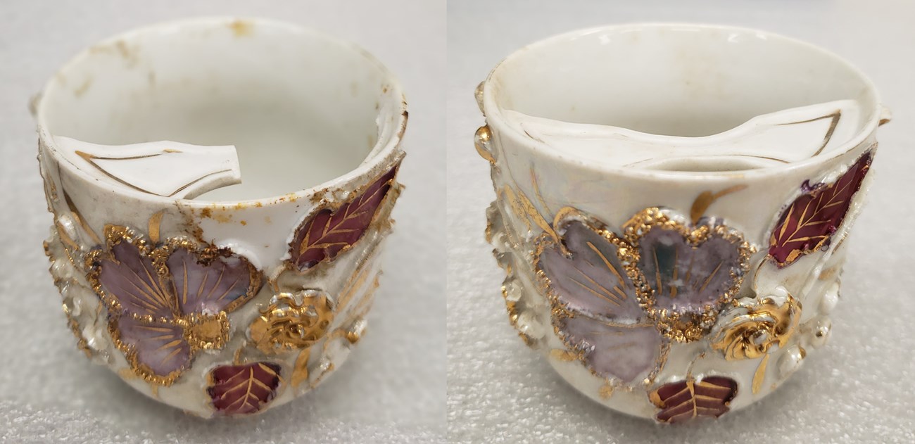 Two fragile looking tea cups with the same raised floral patterns of gold and pink. One has a mustache shield at the top. The other's guard has hand broken off.
