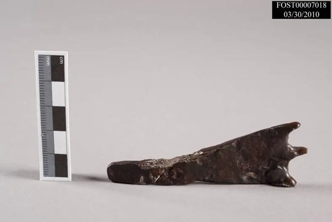 A vaguely triangular piece of rusted metal with small points on the small side.