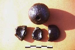 Several rounded mortars and mortar fragments sitting in a pile.