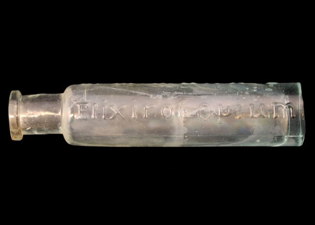 A small, elongated, cylindrical bottle with embossed lettering "Opium"