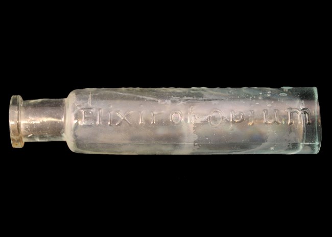 FOST Opium bottle A small, elongated, cylindrical bottle with embossed lettering "Opium"