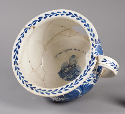 a nicely decorated large tea cup-like object has a handsome man's face at the bottom...this is a 19th century toilet!