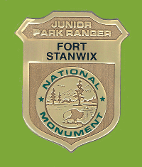 a shiny badge shaped like a shield. on the front: Fort Stanwix National Monument Junior Park Ranger