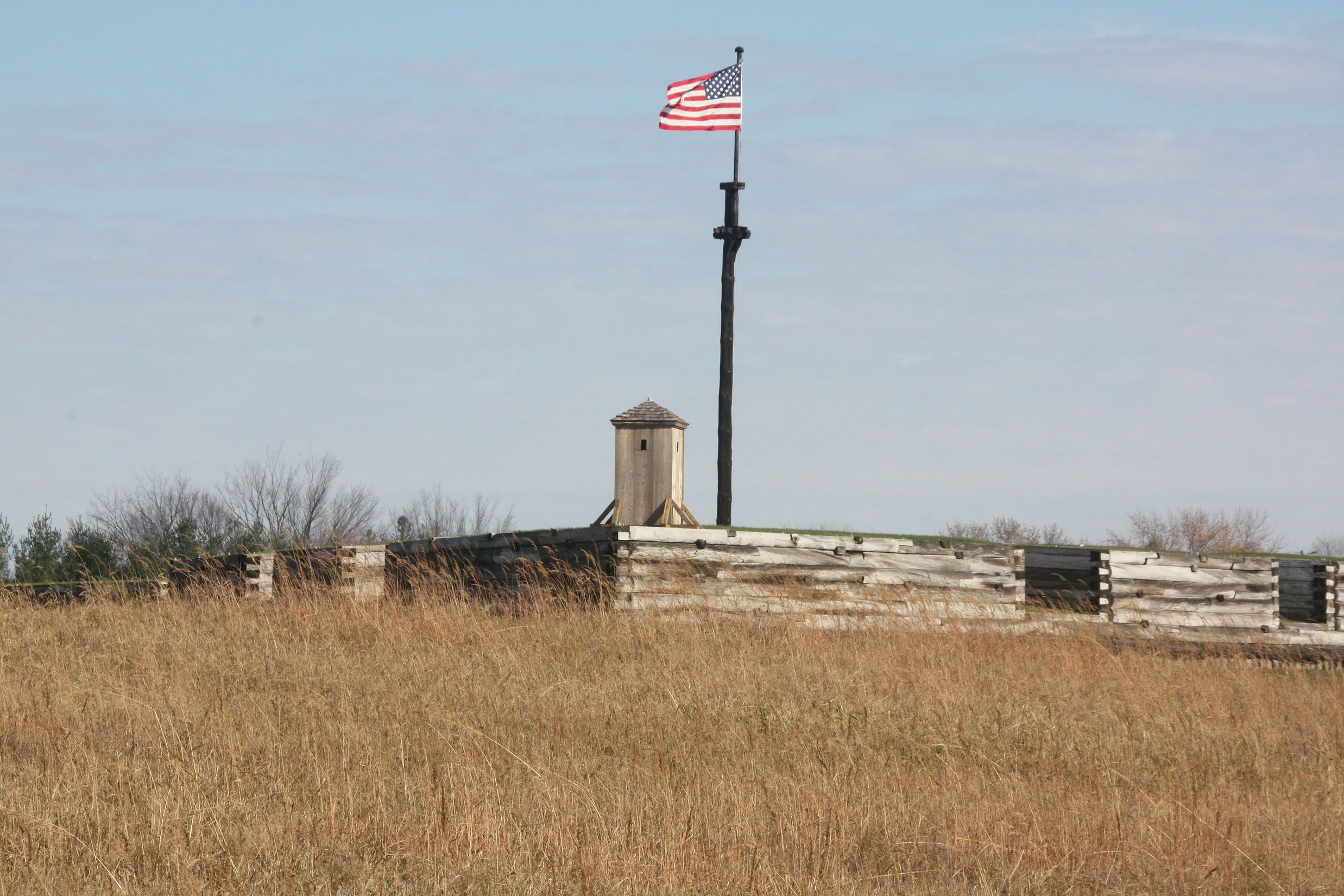 20091107 (1) An American flag flies from a large flag mast over the wood walls of the fort.