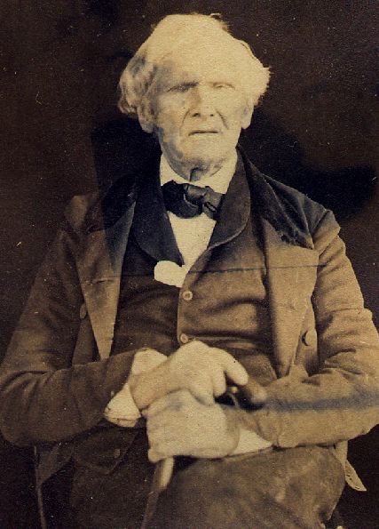 black and white, an old gentleman in a nice suit looks at the camera