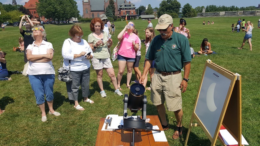 A crowd gathers around a telescope projecting shadows during the 2017 eclipse.