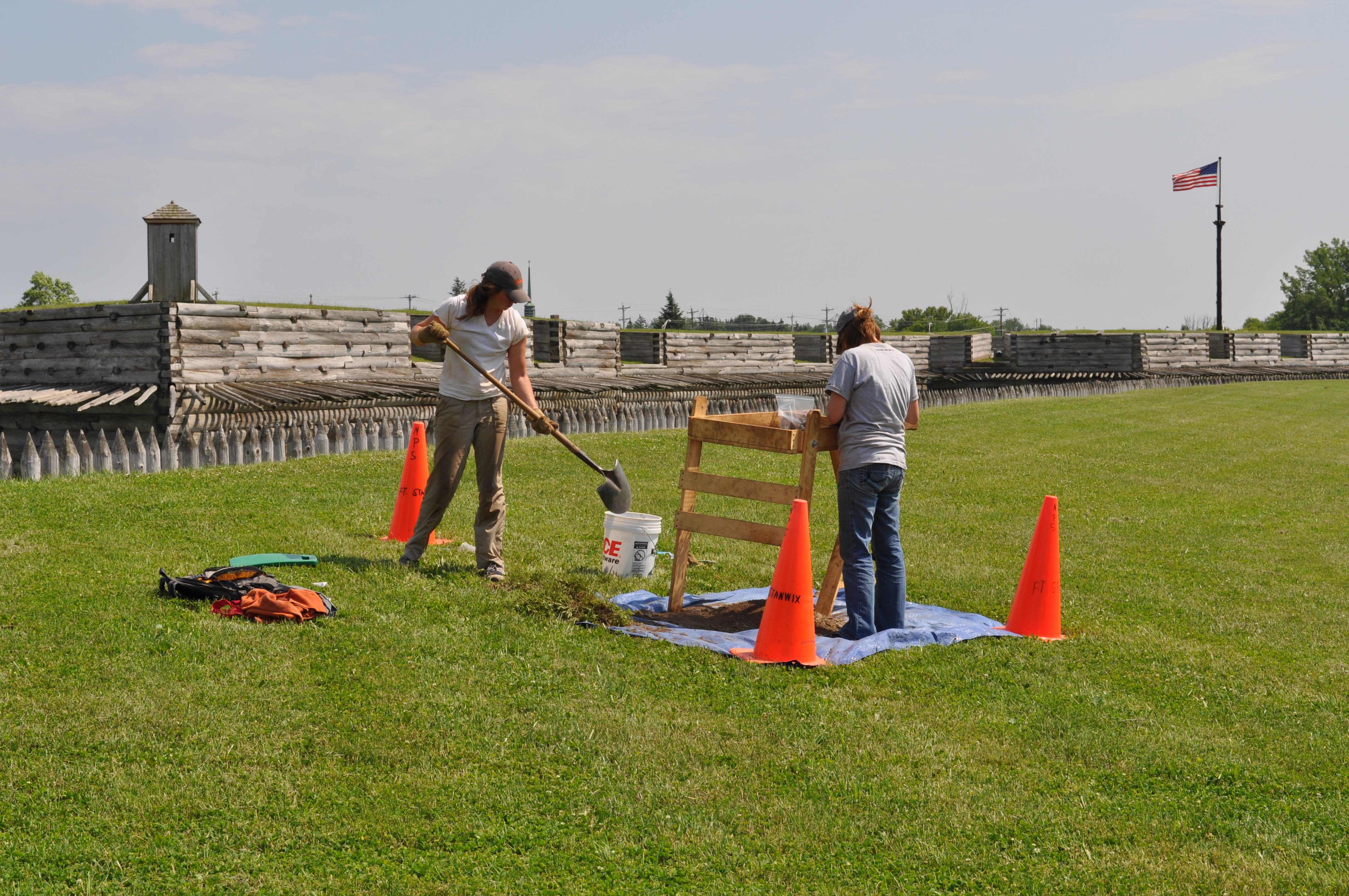 people use shovels to dig holes in a grassy area