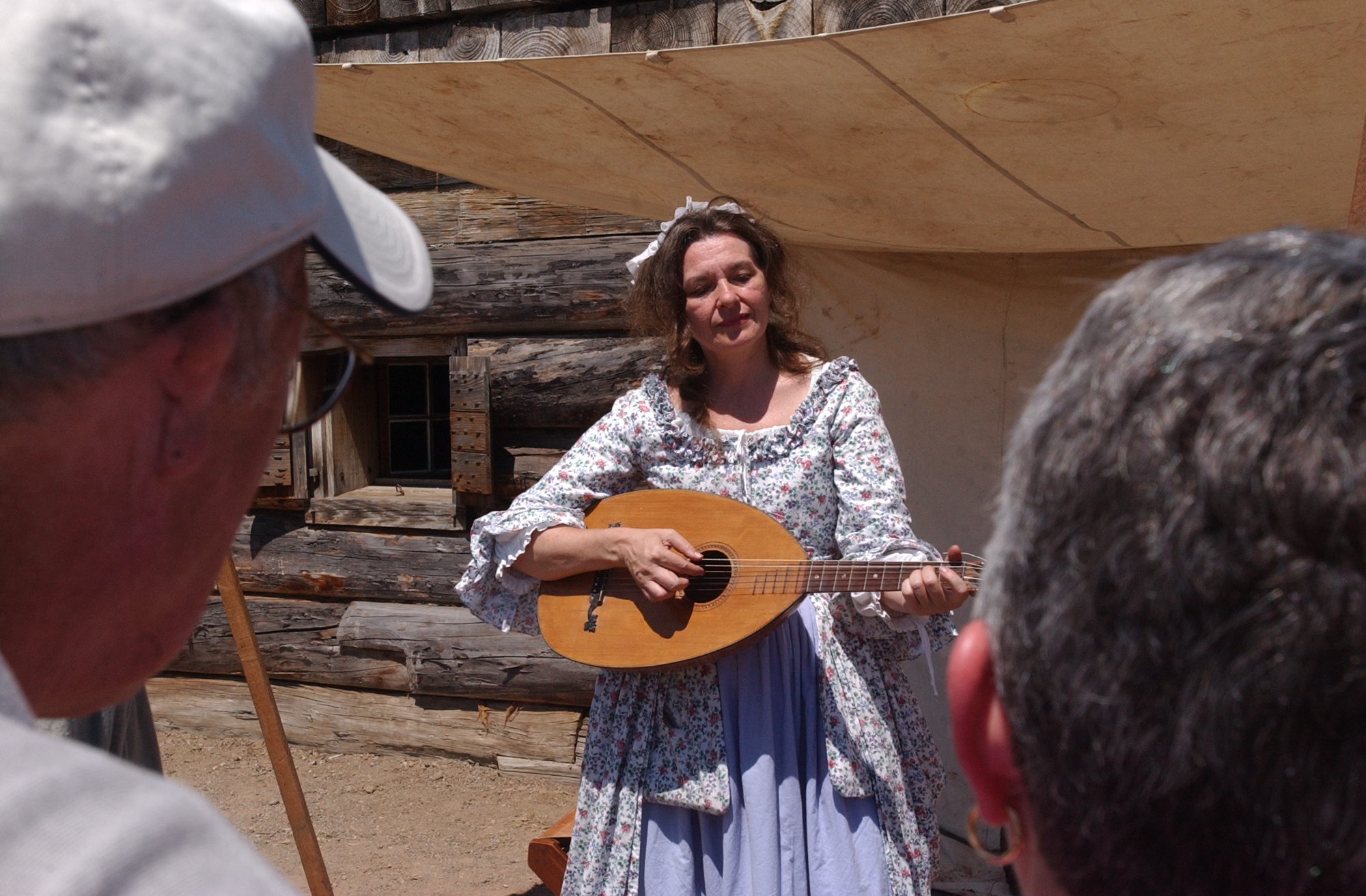 a eye sight view of a woman playing a lute-like instrument in a billowy dress