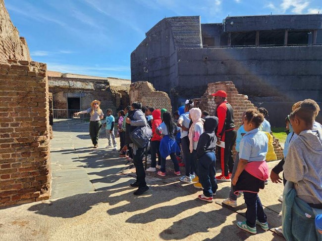 A park ranger leads a group of student through Fort Sumter