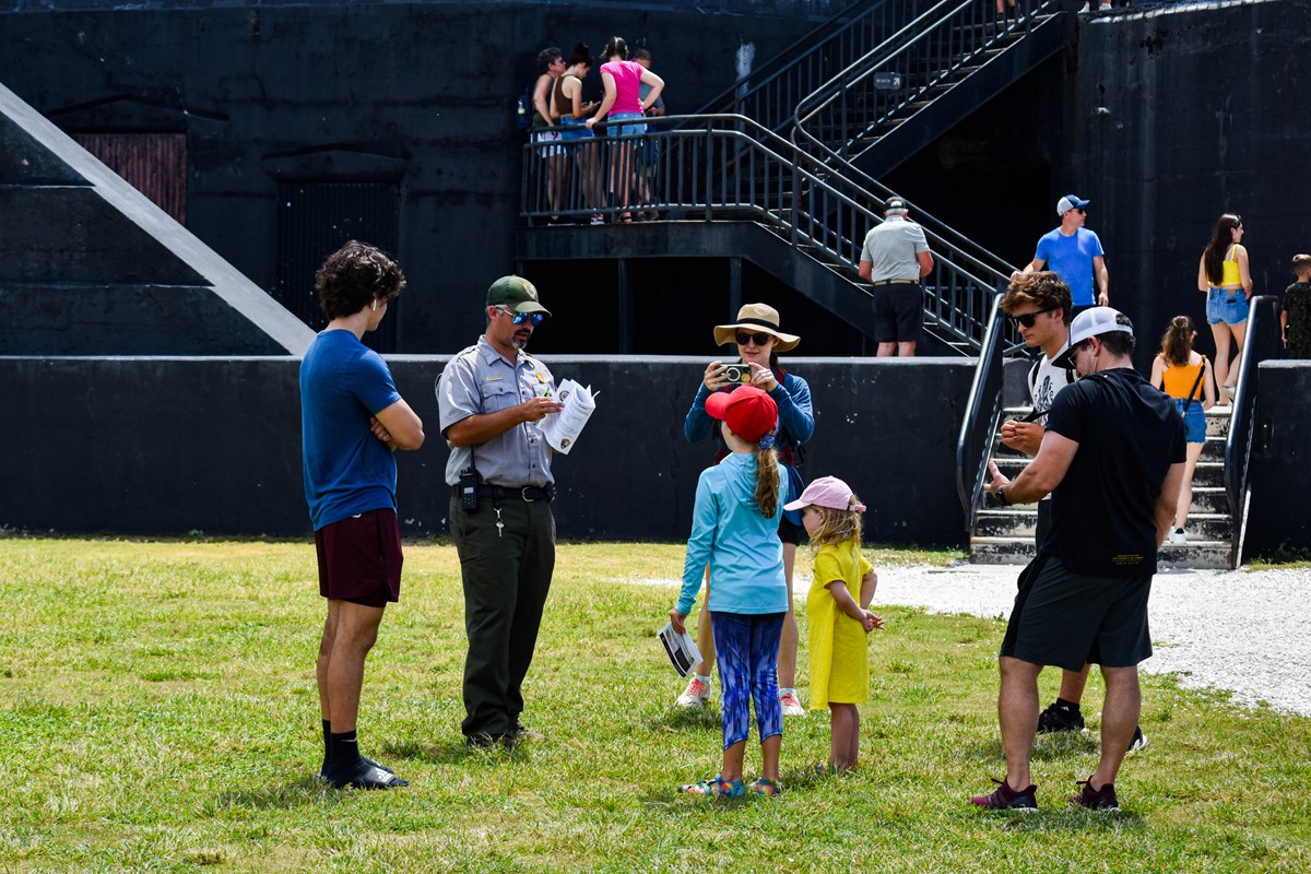 Park Ranger talks to a family in front of a black battery Park Ranger talks to a family in front of a black battery