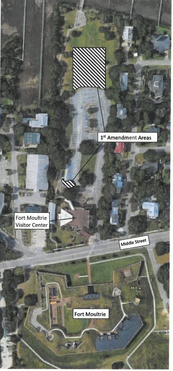 Aerial view of Fort Moultrie Visitor Center and parking lot complex with First Amendment Rights areas marked as a portion of the grass field next to the parking lot and a section of sidewalk between the Visitor Center and accessible parking spaces.