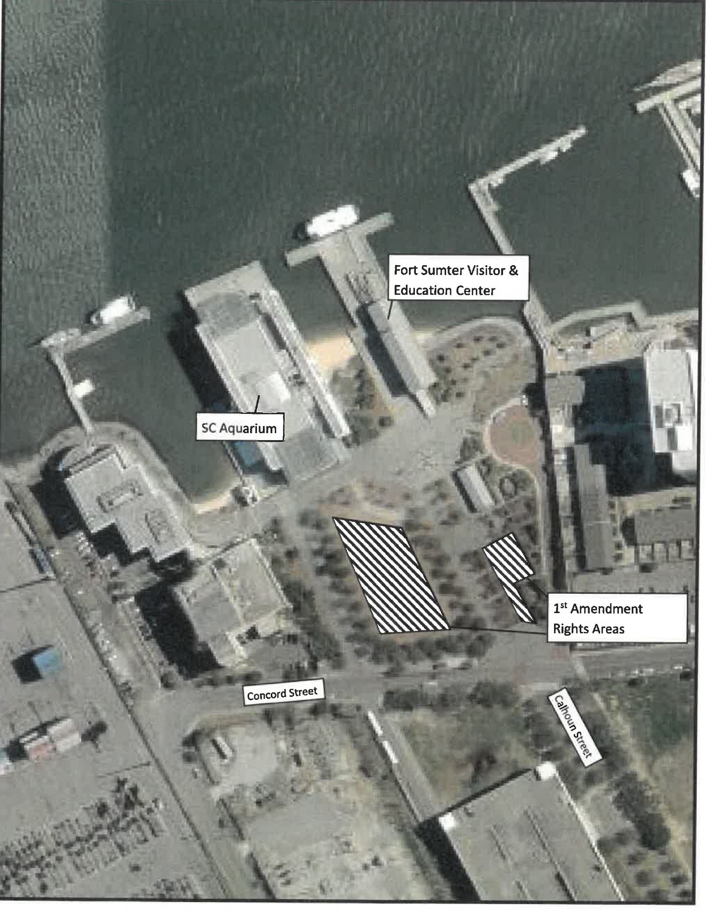 Aerial view of Liberty Square First Amendment Rights areas marked as raised grass area in front of the SC Aquarium and the shade shelter closest to Concord and Calhoun Streets, plus a portion of the sidewalk to the left of the shade shelter.