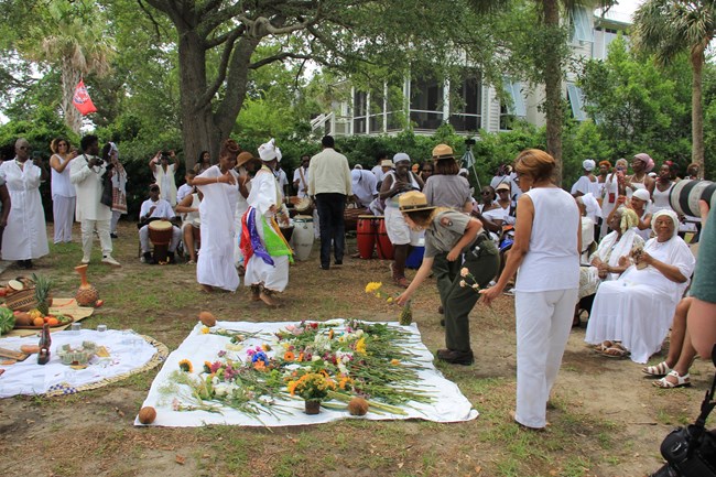 A ranger places a flower in a pile of flowers during the Remembrance Commemoration