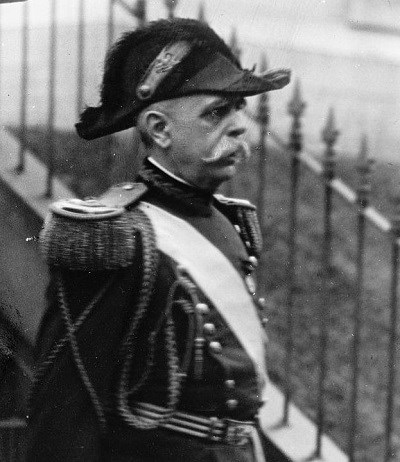 Black and White Photo of older mustached man wearing a military uniform and fluffy black bicorn hat.