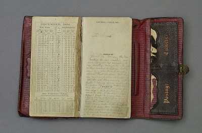 Trifold Leather datebook opened up to a December 1864 calendar on one side and Booth's diary entries on the other.