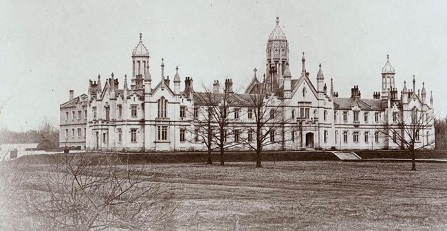 Photo of a 19th century ornamented Gothic style college building with three steeples