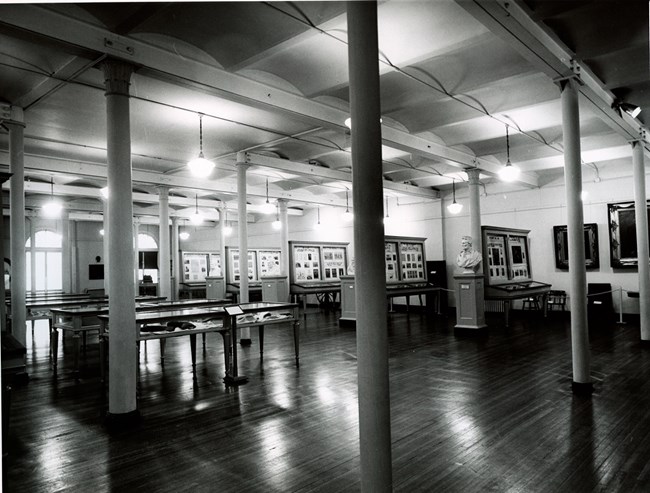 Photo of an open hall with support columns and display cases with Lincoln memorabilia