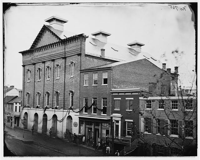 Photo of 19th-century Brick Theatre building with mourning ribbons across the windows