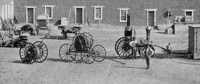 3 men standing next to 19th-century fire engine
