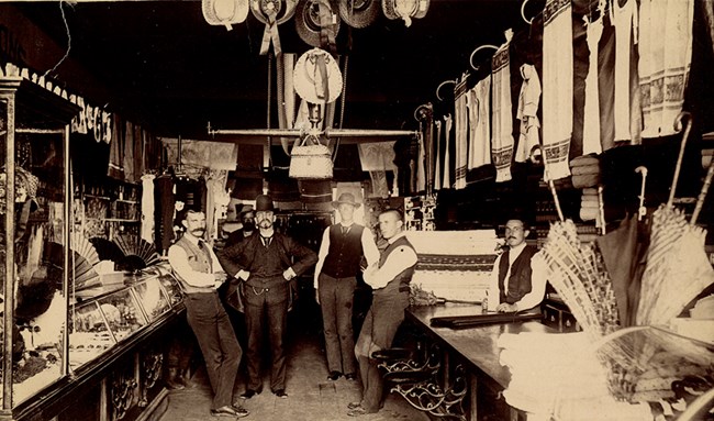 clerks standing in 19th shop surrounded by mechandise