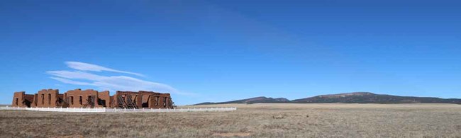 A series of fur of five low peaks on moutains with an adobe building in the foreground .